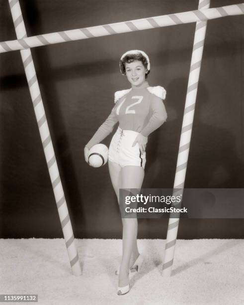 1950s 1960s WOMAN IN SEXY FOOTBALL COSTUME AT GOAL POST LOOKING AT CAMERA