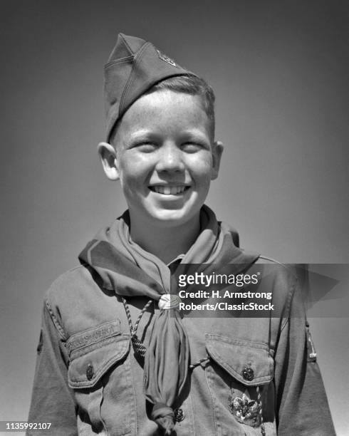 1950s SMILING PRETEEN BOY SCOUT IN UNIFORM CAP SHIRT NECKERCHIEF STANDING LOOKING AT CAMERA