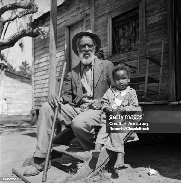 1930s ELDERLY MAN GRANDFATHER SIT PORCH SHACK WITH GRANDSON BOY LOOKING AT CAMERA