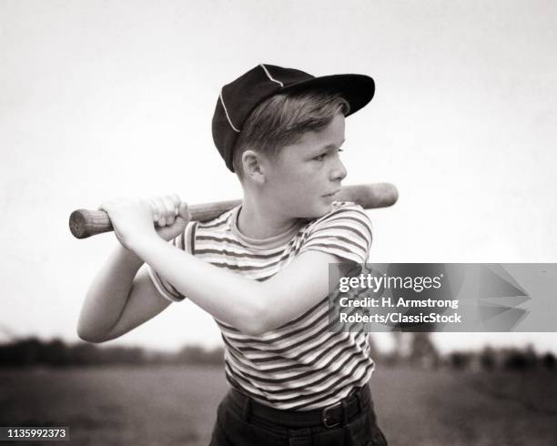 1930s PORTRAIT SERIOUS PRETEEN BOY WEARING BASEBALL CAP AND STRIPED T-SHIRT HOLDING BASEBALL BAT WATCHING WAITING FOR THE PITCH