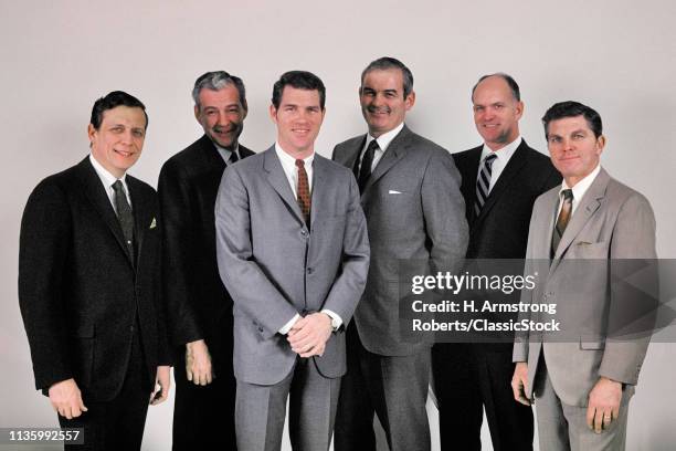 1960s SIX BUSINESSMEN EXECUTIVE GROUP ALL CAUCASIAN WEARING SUITS STANDING IN LINE SMILING LOOKING AT CAMERA