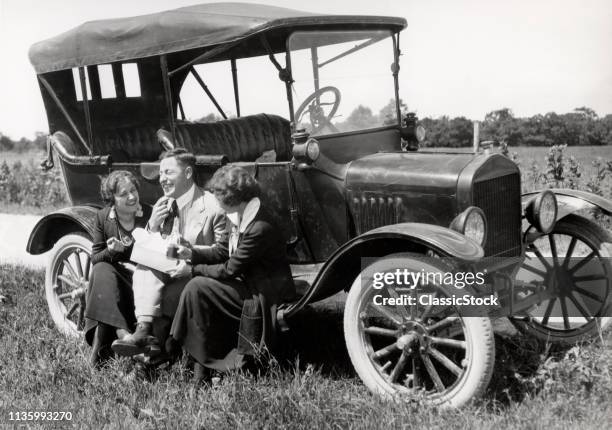 1920s TWO WOMEN & ONE MAN SITTING ON RUNNING BOARD OF MODEL T FORD EATING LUNCH TALKING & LAUGHING