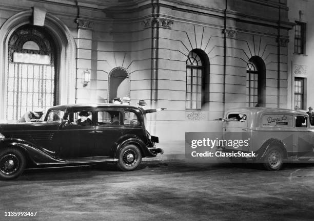 1930s MOVIE STILL OF NIGHTTIME SHOOTOUT BETWEEN GANGSTERS IN A PARKED CAR AND A PASSING PANEL TRUCK