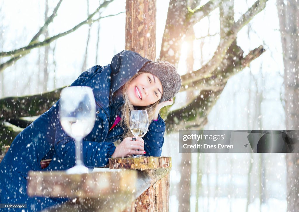 Woman drinking wine in log cabin in snowy day