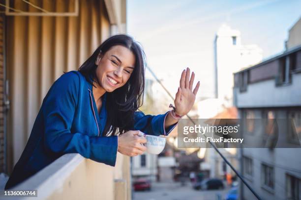 smiling neighbor waving while enjoying a cup of coffee - neighbor stock pictures, royalty-free photos & images