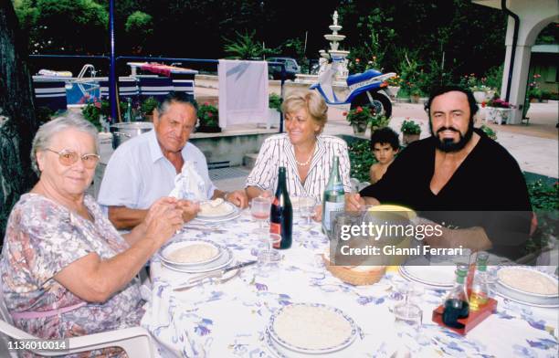 Italian tenor Luciano Pavarotti sits with, from left, his parents, Adele and Fernando Pavarotti , and wife, Adua Pavarotti, as they dine outdoors at...