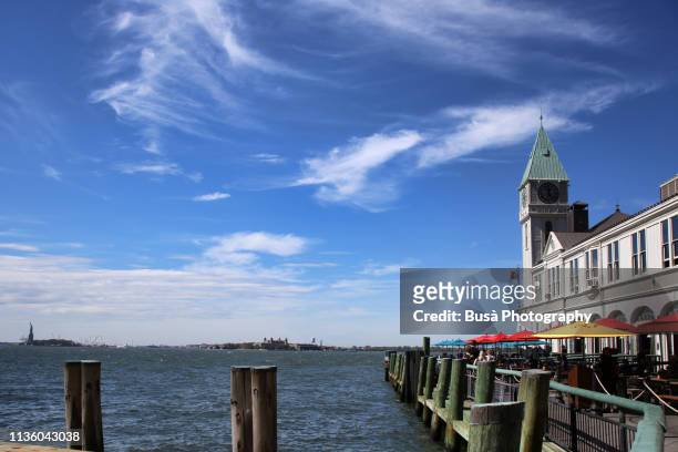 view towards ellis island from pier a harbor house in lower manhattan along the hudson river. new york city, usa - waterfront dining stock pictures, royalty-free photos & images