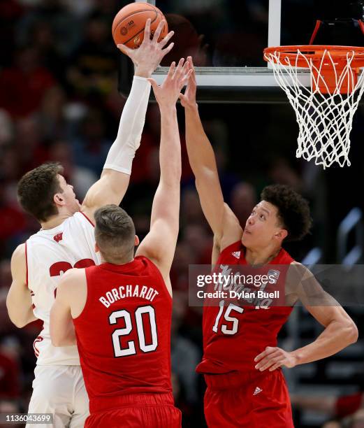 Ethan Happ of the Wisconsin Badgers attempts a shot while being guarded by Tanner Borchardt and Isaiah Roby of the Nebraska Huskers in the second...