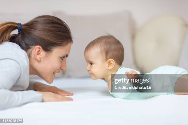 mutter und baby spielen auf dem bett - baby playing stock-fotos und bilder