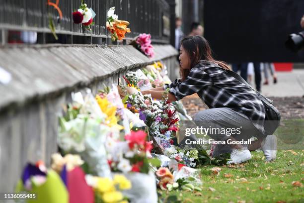 People gather to lay flowers outside the Botanic Gardens on March 16, 2019 in Christchurch, New Zealand. At least 49 people are confirmed dead, with...