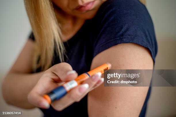 young woman injecting insulin in hers arm - insulin pen stock pictures, royalty-free photos & images