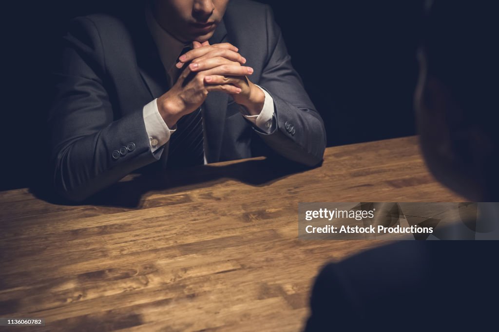 Detective interviewing suspect in dark room