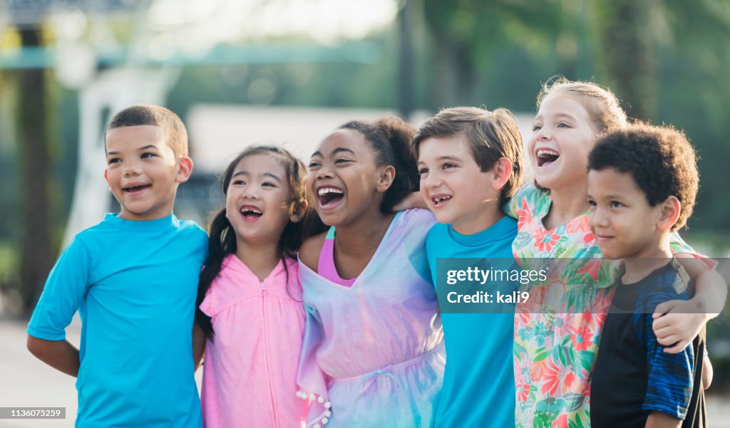 Six multi-ethnic children standing at swimming pool