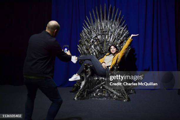 Invited guests pose on the Iron Throne at the Game Of Thrones: The Touring Exhibition launch at Titanic Exhibition Centre on April 10, 2019 in...