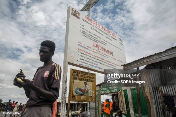 Refugee seen standing in front of a sign warning against corruption in Kakuma refugee camp, northwest Kenya. Kakuma is home to members of the local...