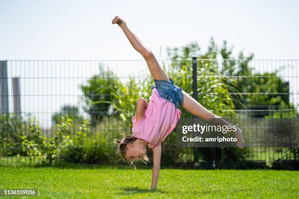 child girl doing one hand cart wheel in garden - cartwheel stock pictures, royalty-free photos & images
