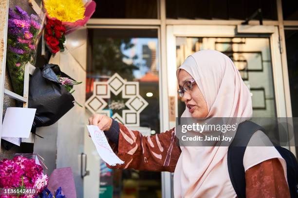 Syima Mansor reads a note after prayer, as flowers and cards are left outside the mosque at the Islamic Council of Victoria on March 16, 2019 in...