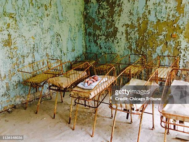 Rusting crib containing a baby doll and blanket sits in the Pripyat hospital maternity ward.