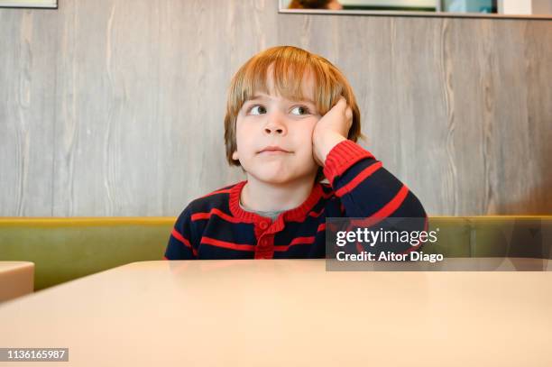 thinking boy (6years) sitting at a restaurant table - boys only caucasian ethnicity 6 7 years stock pictures, royalty-free photos & images