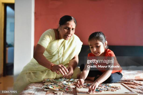 grandmother and granddaughter solving the puzzle pieces - asian games day 2 stock-fotos und bilder