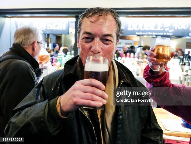Nigel Farage enjoys a pint with fellow walkers as they arrive at the end of the first leg of the March to Leave campaign on March 16, 2019 in...