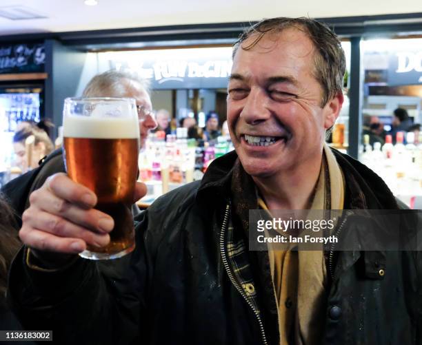 Nigel Farage enjoys a pint with fellow walkers as they arrive at the end of the first leg of the March to Leave campaign on March 16, 2019 in...