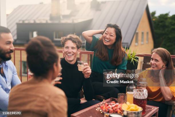 cheerful friends talking while enjoying social gathering on terrace - building terrace stock pictures, royalty-free photos & images