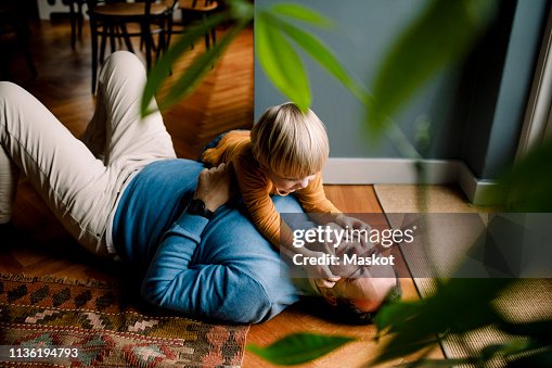 Playful daughter pinching cheerful father's cheeks on floor at home Playful daughter pinching cheerful father's cheeks on floor at home