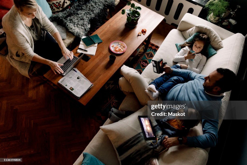 High angle view of family using various technologies in living room at home