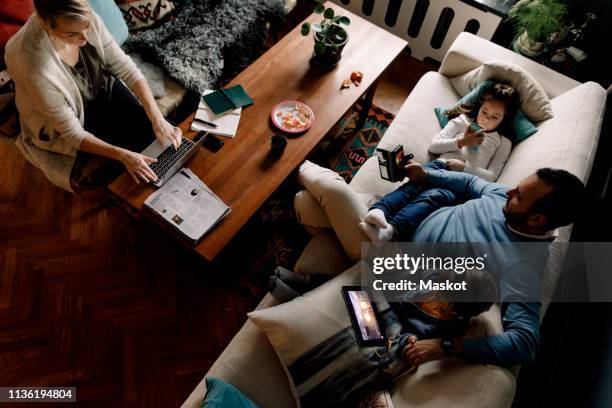 high angle view of family using various technologies in living room at home - family tablet bildbanksfoton och bilder