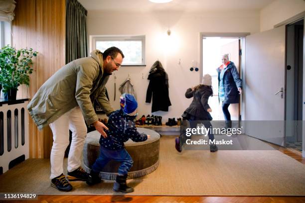 playful siblings with parents in mudroom at home - winter family home fotografías e imágenes de stock