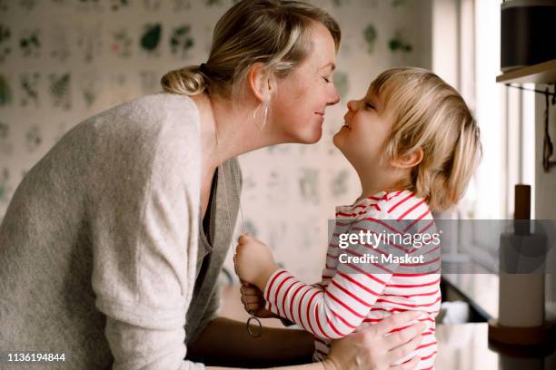 side view of playful mother and daughter spending leisure time in kitchen at home - contemplation family stockfoto's en -beelden