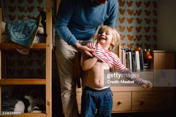 father dressing cheerful daughter at home - help getting dressed stock pictures, royalty-free photos & images