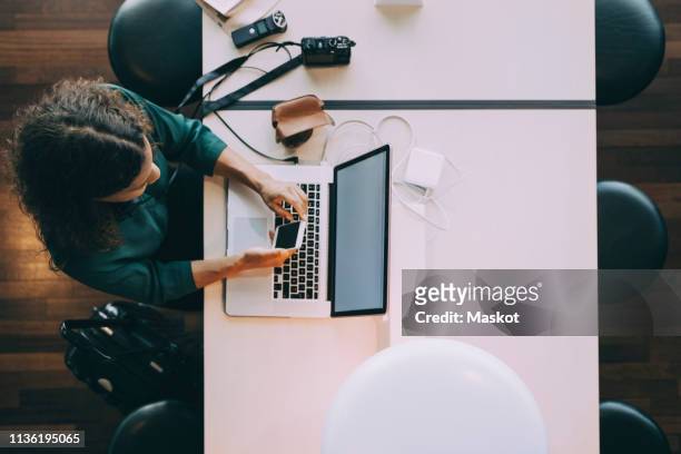 directly above view of businesswoman using smart phone while sitting with laptop at airport - airport from above stock pictures, royalty-free photos & images