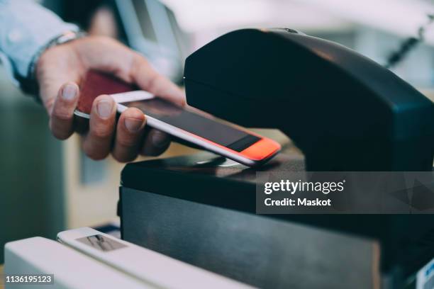 cropped hands of businessman scanning ticket on smart phone at airport check-in counter - booth stockfoto's en -beelden