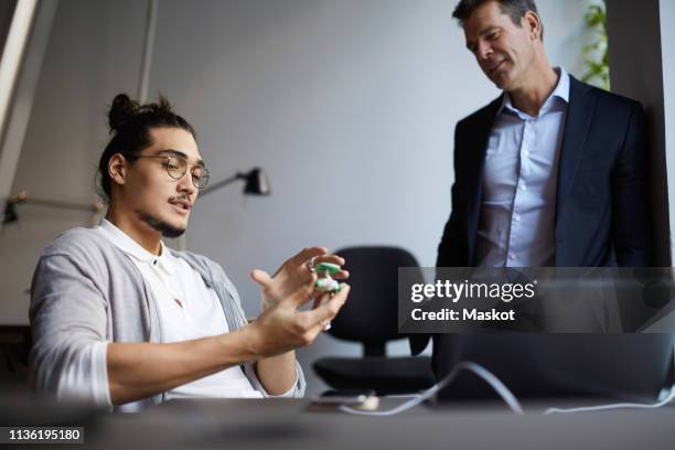 male entrepreneur discussing with bank manager over solar toy car in creative office - private equity stock pictures, royalty-free photos & images