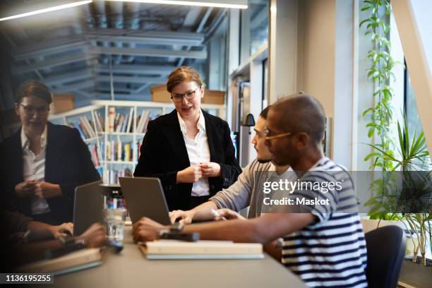 male entrepreneurs giving presentation to female bank manager over laptop at desk in creative office - private equity stock-fotos und bilder