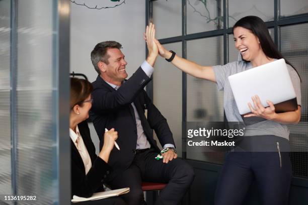 cheerful creative businesswoman high-fiving with male bank manager during meeting in office - sales pitch stock pictures, royalty-free photos & images