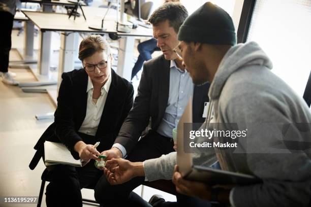 male entrepreneur showing solar toy car to bank managers during meeting in creative office - venture capital stock-fotos und bilder