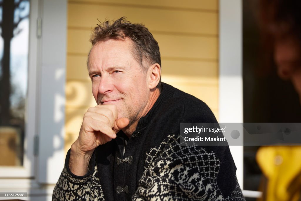 Thoughtful mature man looking away while sitting on porch