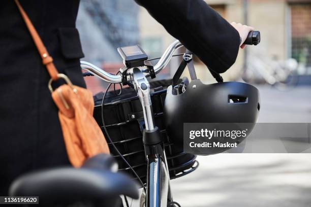 midsection of woman walking with electric bicycle in city - sports helmet stock pictures, royalty-free photos & images