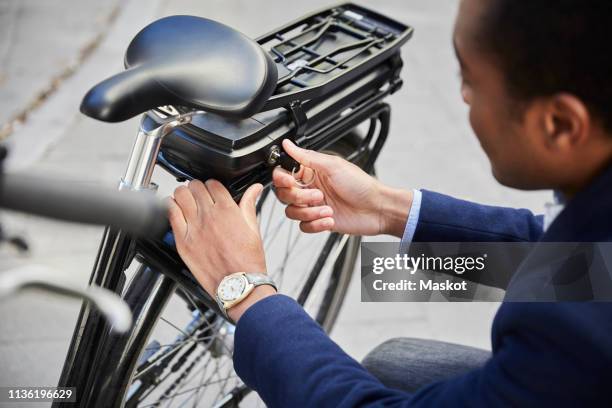 high angle view of young male commuter locking electric bicycle in city - ebike stockfoto's en -beelden