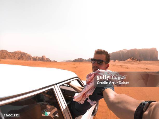 traveler guy taking a selfie from out of the car driving in the wadi rum desert. - action camera stock pictures, royalty-free photos & images