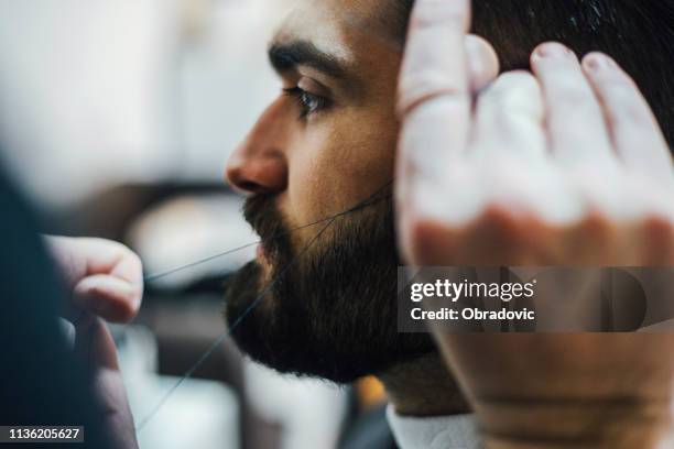 crop barber threading eyebrows of client - threading eyebrows stock pictures, royalty-free photos & images