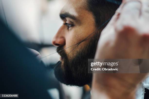crop barber threading eyebrows of client - threading eyebrows stock pictures, royalty-free photos & images