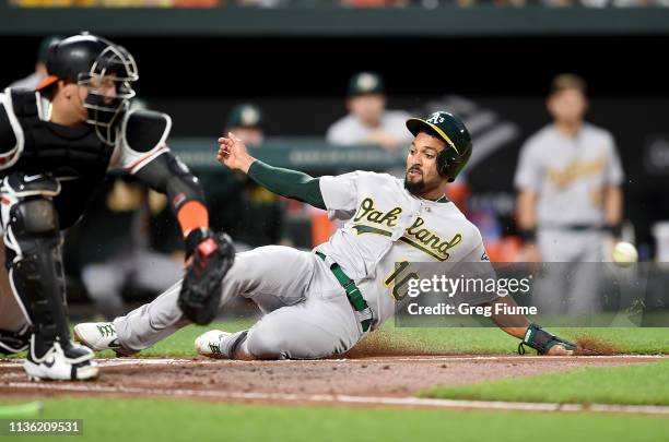 Marcus Semien of the Oakland Athletics scores ahead of the throw to Jesus Sucre of the Baltimore Orioles in the third inning at Oriole Park at Camden...