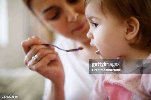 moeder voederen haar baby - spoon feeding stockfoto's en -beelden