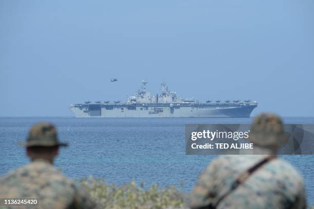 Marines watch the US navy multipurpose amphibious assault ship 'USS Wasp' with F-35 lightning fighter jets on the deck during the amphibious landing...