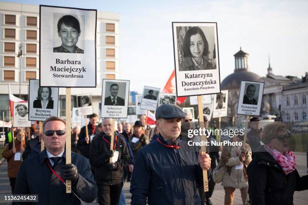 People hold images of victims of a plane crash during celebrations of anniversary of presidental plane crash near Smolensk in Warsaw on April 10,...