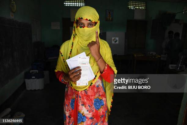 An Indian Muslim woman shows her ink-marked finger after casting her vote at a polling station during India's general election in Samuguri, some 155...